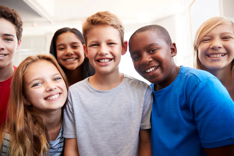 A group of elementary school children crowding before the camera and smiling.