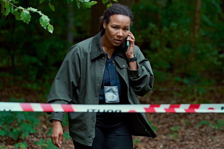 a woman on the phone walks behind a police tape