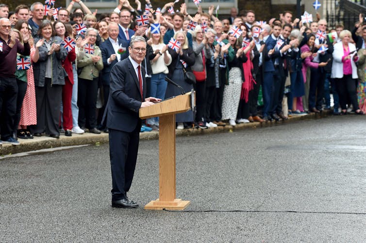 Keir Starmer speaking in front of a large crowd on Downing Street.
