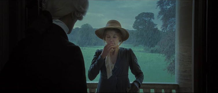 Una mujer estornuda en el marco de una puerta.