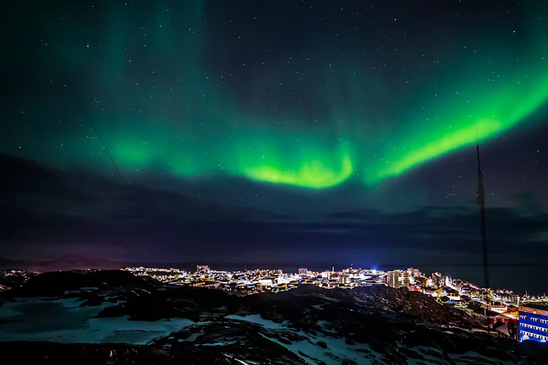 Luces verdes en el cielo sobre una ciudad de noche