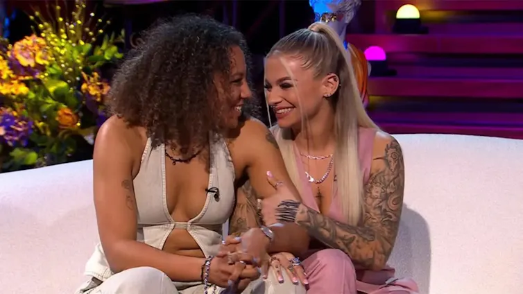 two women snuggle together on a couch, they are looking into each other's eyes
