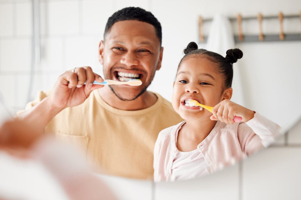 Man and child smiling and brushing teeth
