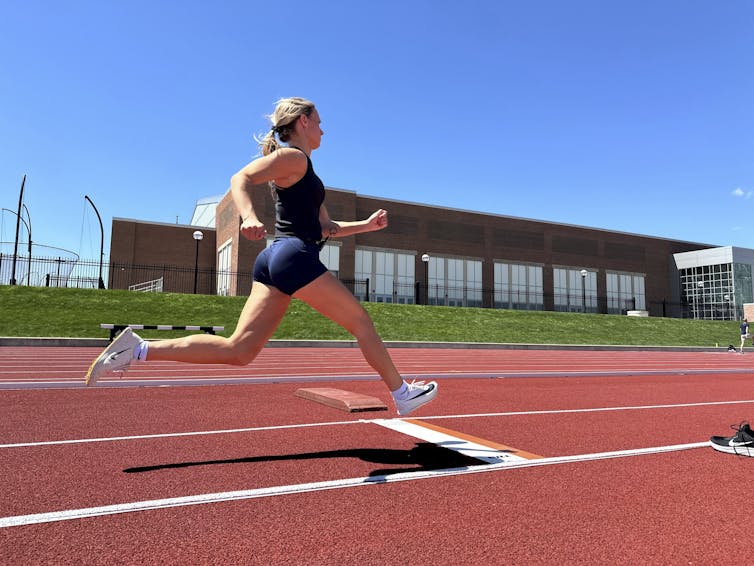 A blonde woman sprints down a track