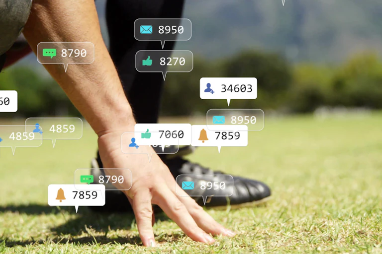 Social media notifications are laid over a photo of an athlete's hand touching grass beside a cleated foot