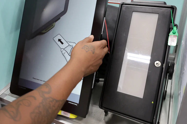 an arm extends, hand on the edge of the larger of two side-by-side vertical display screens