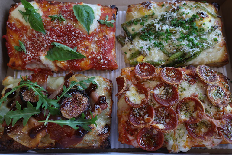 Four square pizzas, each with different toppings, are seen in a photograph taken on May 19, 2025.
