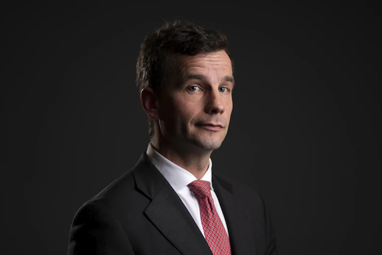 Portrait of politician David Seymour against a black background.