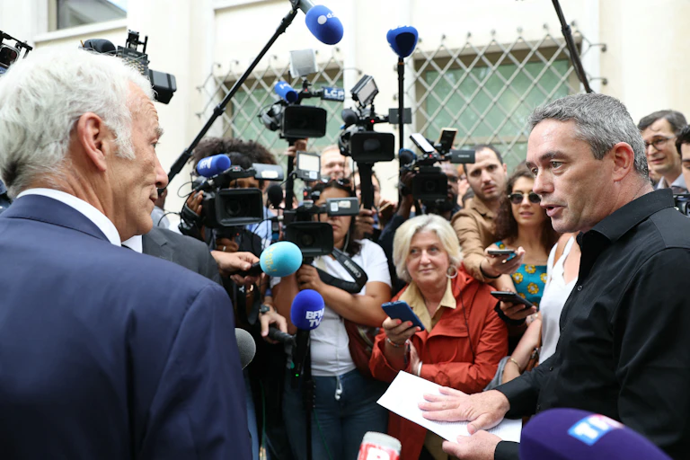 Deux hommes se font face devant les caméras et micros de télévision.