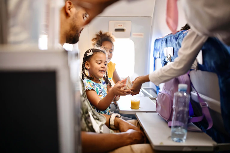A girl on a flight is handed a sandwich.