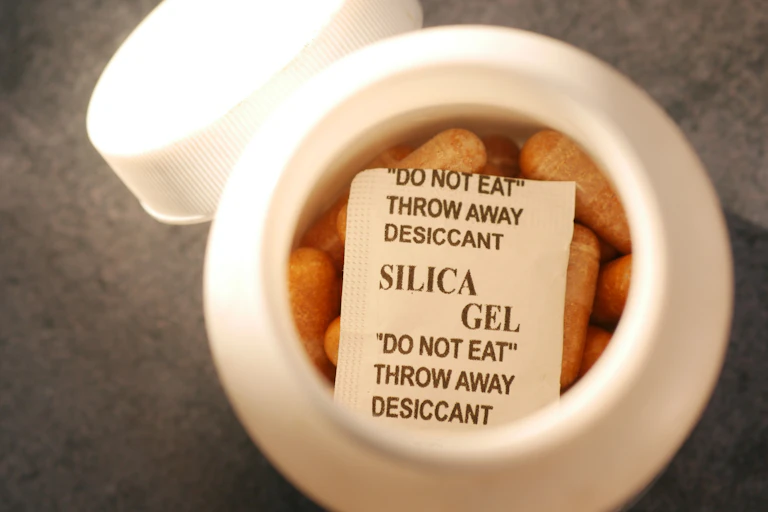 Close-up of a tablet container with silica gel packet on top.