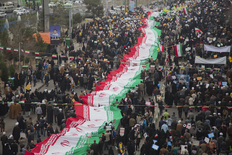 A huge crowd of people with a massive Iranian flag running through their centre.