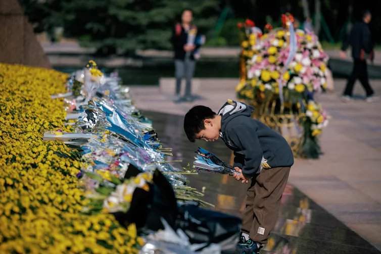 A boy places flowers on a monument to commemorate Chinese martyrs.