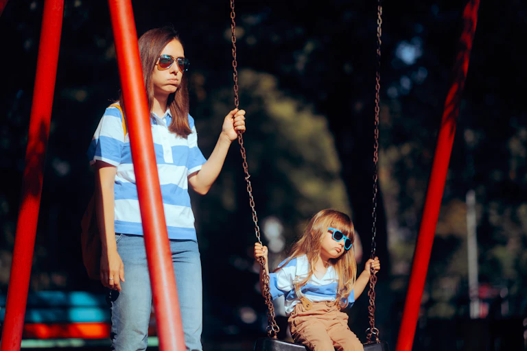 Madre e hija aburridas en un parque infantil