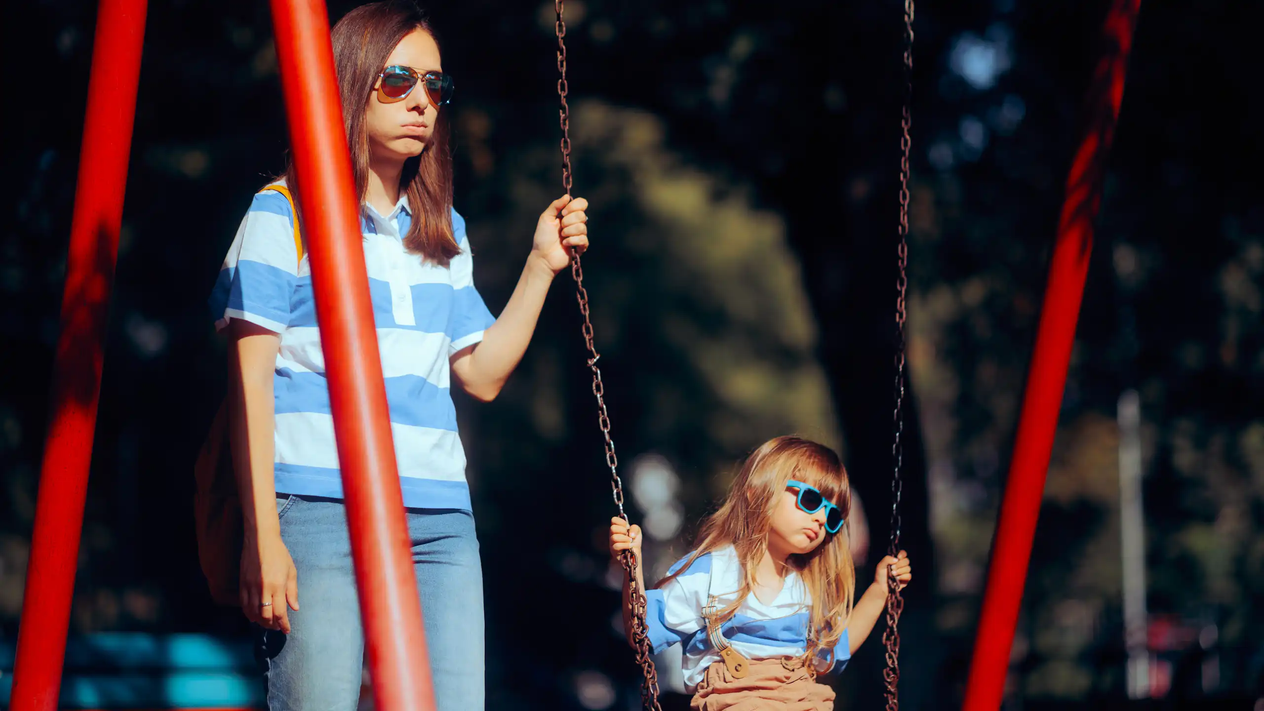 Madre e hija aburridas en un parque infantil