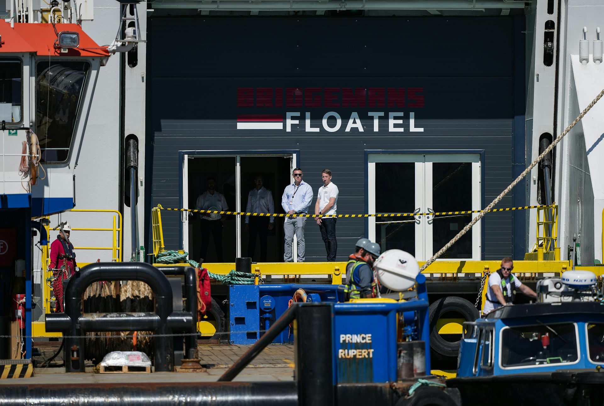 two men stand on a vessel under the letters FLOATEL