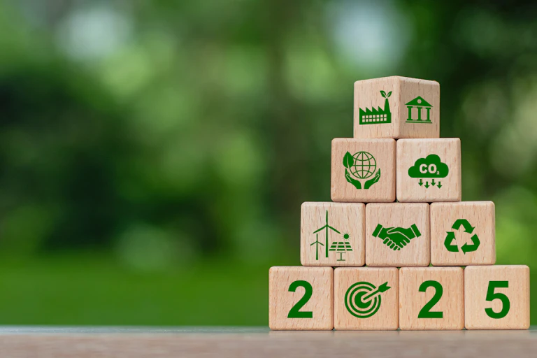 environmental logos on wooden blocks with 2025, green leafy blurred background