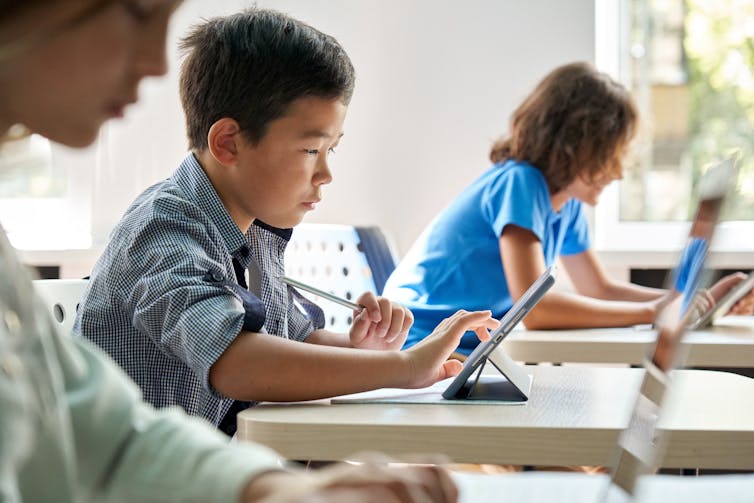 A young boy in a classroom using a laptop
