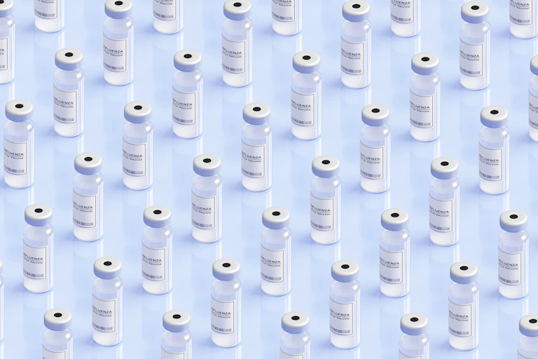 Influenza vaccine bottles lined up in rows on a white table
