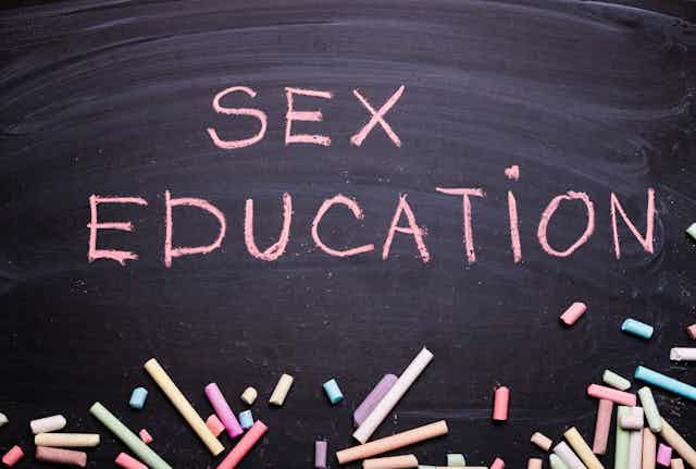 The words "Sex Education" written in pink chalk on a blackboard.