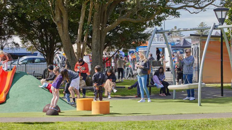 Children playing in a fenced playground in New Zealand.