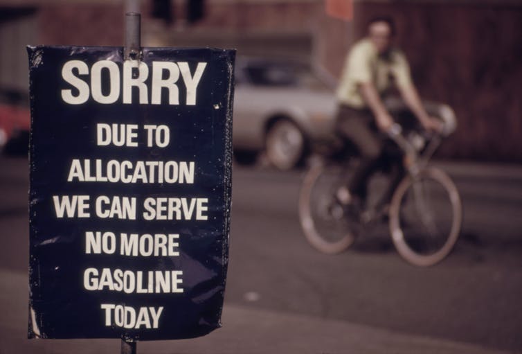 man cycling next to sign saying no more gasoline, Oil Shock.