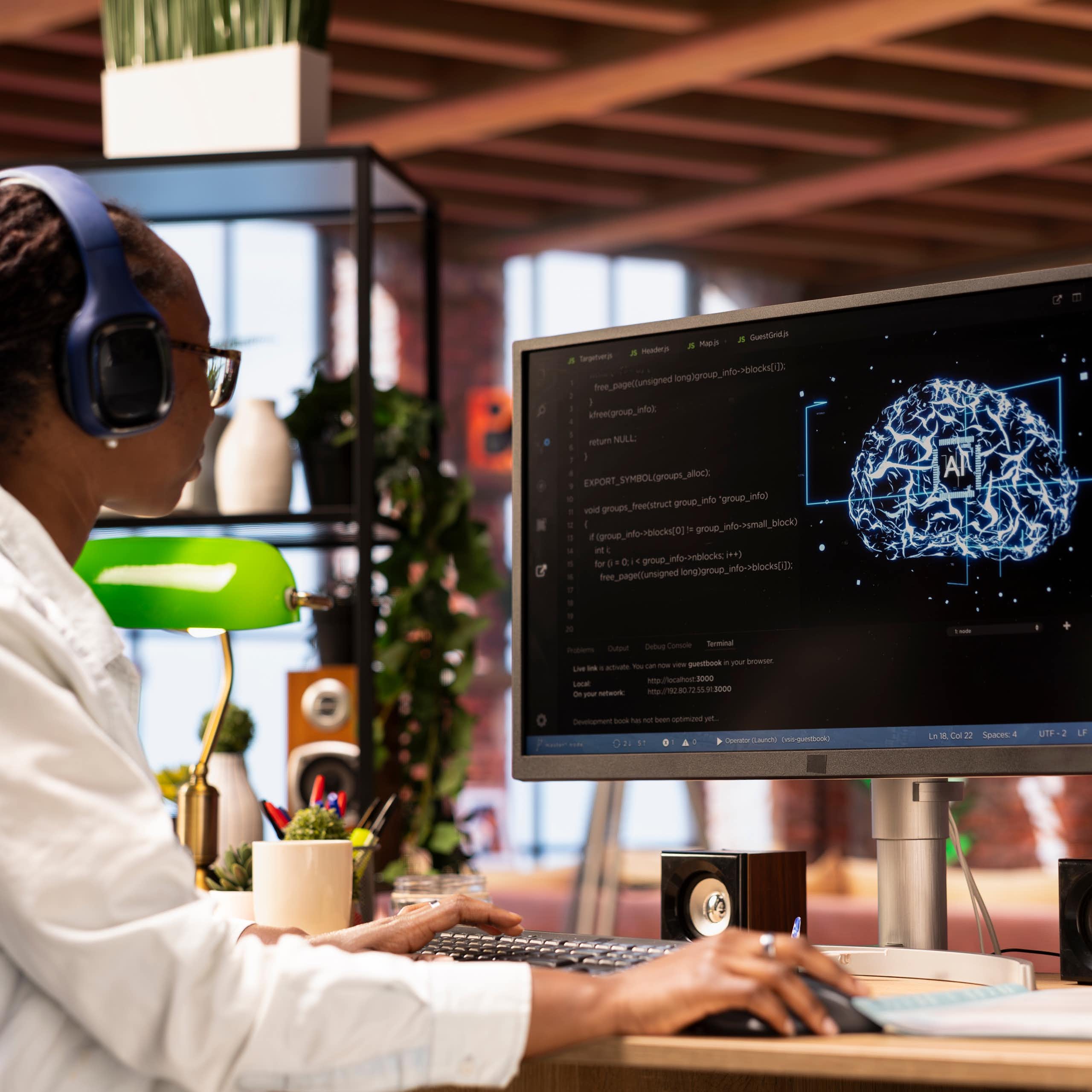 Mujer joven negra con gafas y auriculares mira una pantalla de ordenador con un cerebro digital dibujado con el símbolo de "AI" en el centro