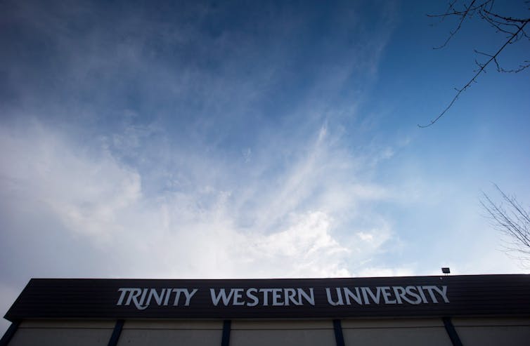 El borde siluetado de un edificio universitario visto debajo del cielo con nubes masculinas.
