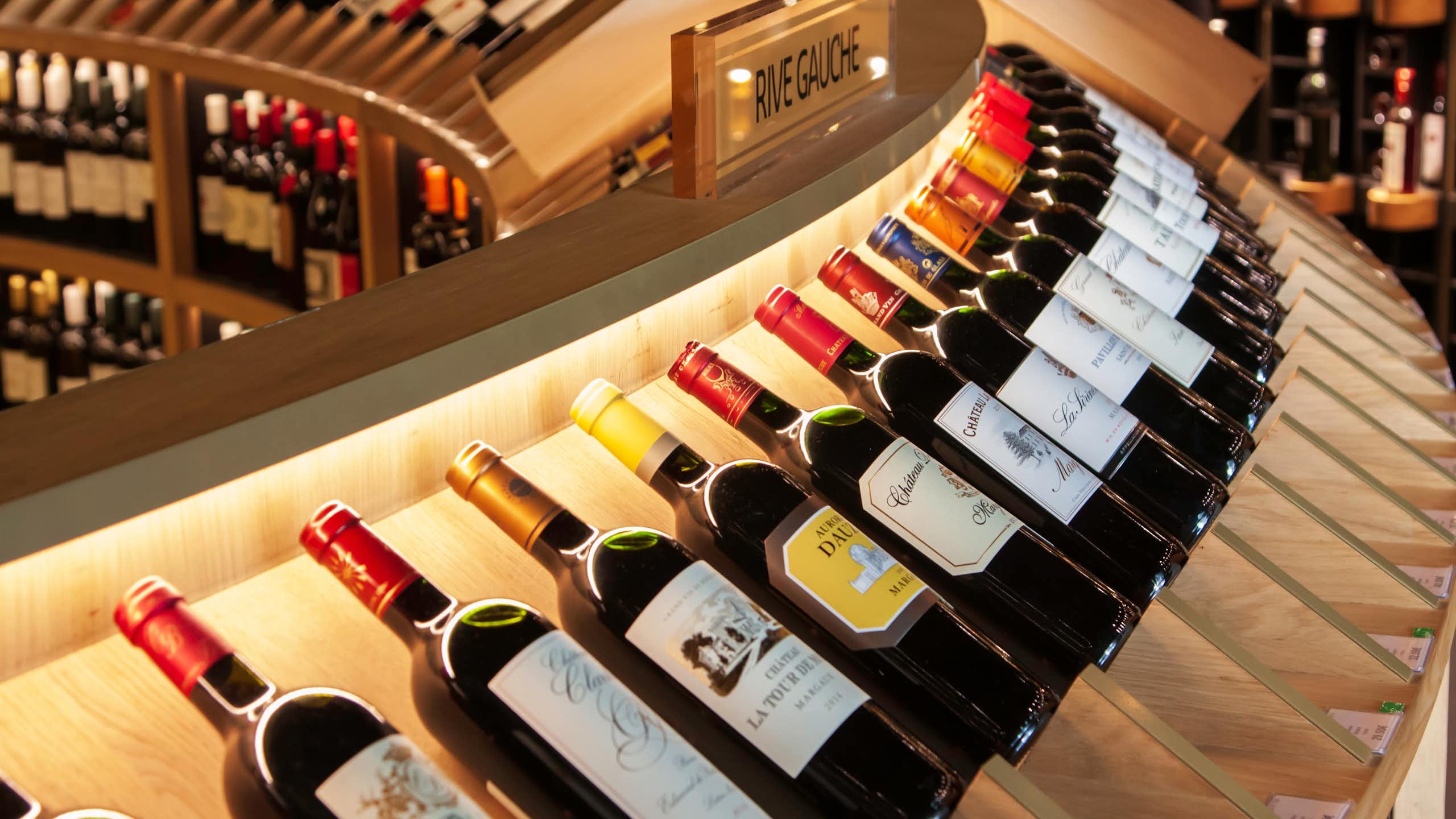 A curved row of bottles of wine on display in a wine shop.