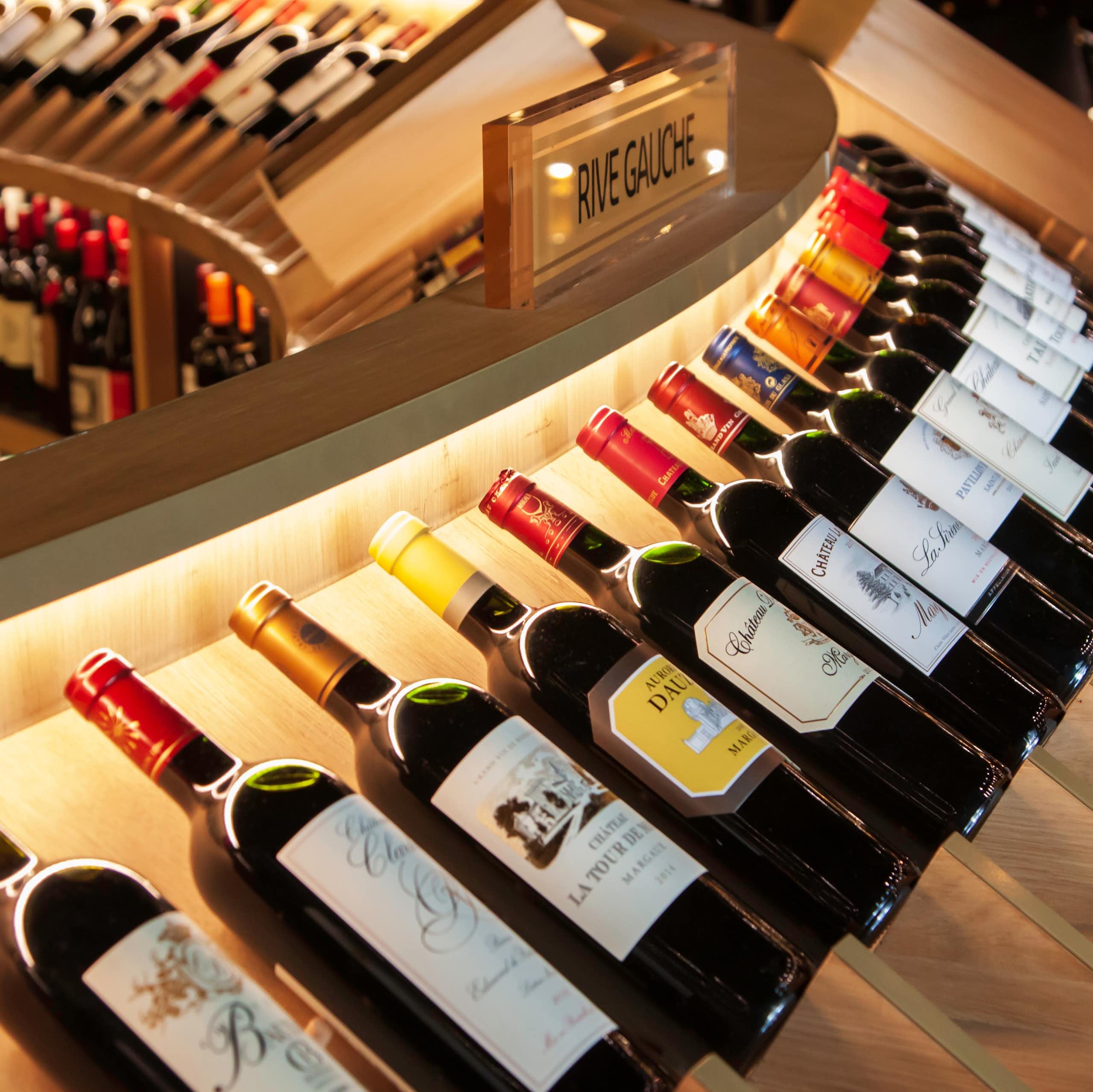 A curved row of bottles of wine on display in a wine shop.