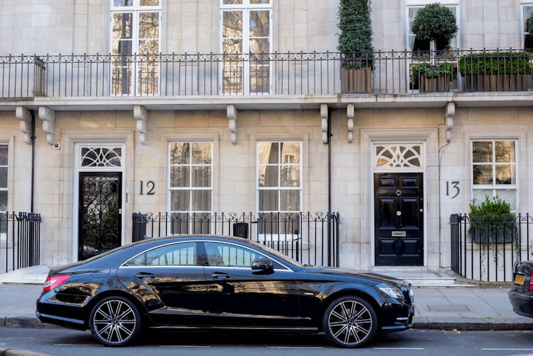 black mercedes car parked outside an expensive terraced home