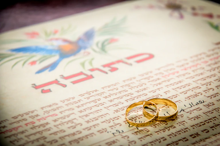 A beautifully illustrated parchment with a bird on the top and two gold rings positioned on the page.