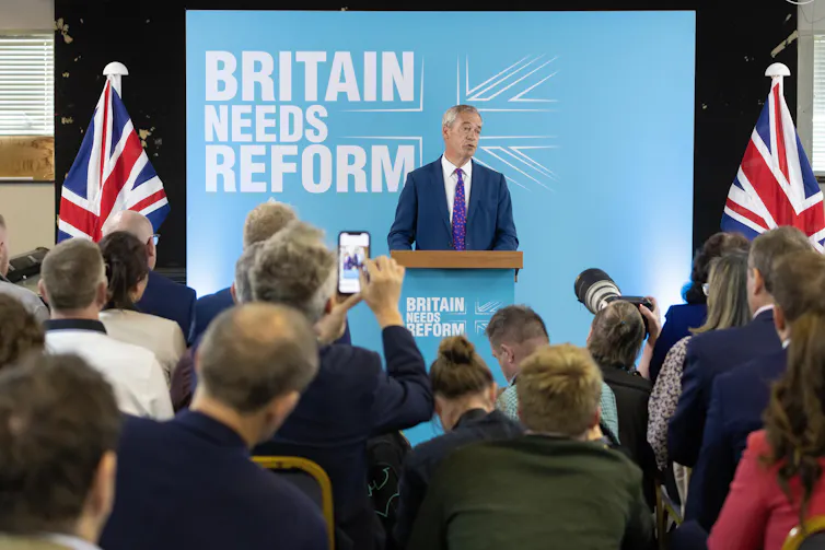 Nigel Farage giving a speech in front of a sign reading 'Britain needs Reform'.