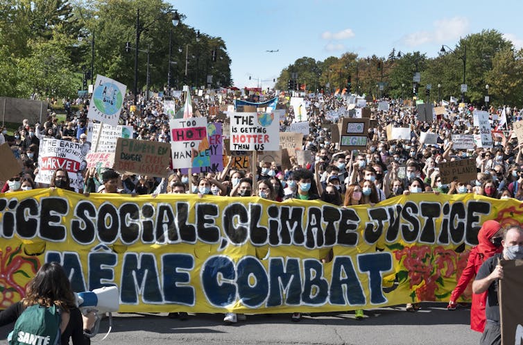 Un gran grupo de personas en protesta con una gran transparencia: la justicia climática