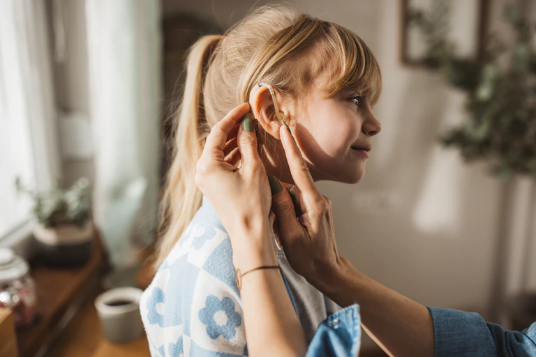 Girl has hearing aid fitted by carer
