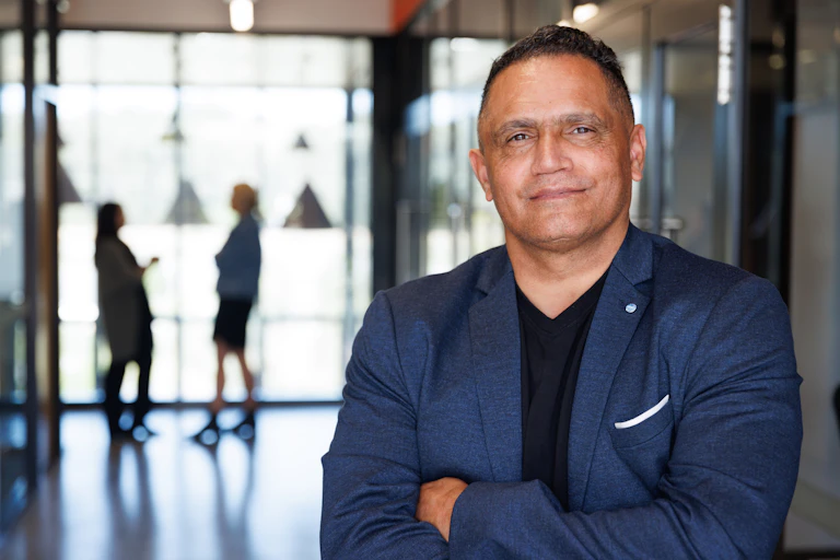 First Nations man in business suit standing in office with arms crossed