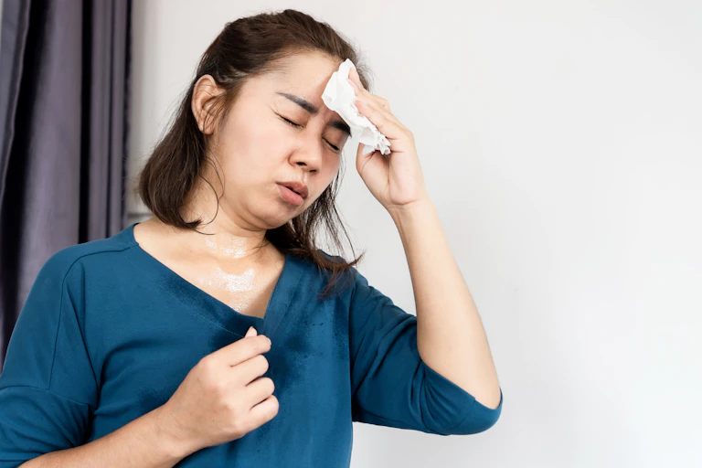 A woman blots sweat off of her forehead.
