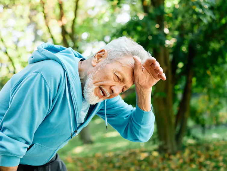 An elderly man wipes sweat off his forehead.