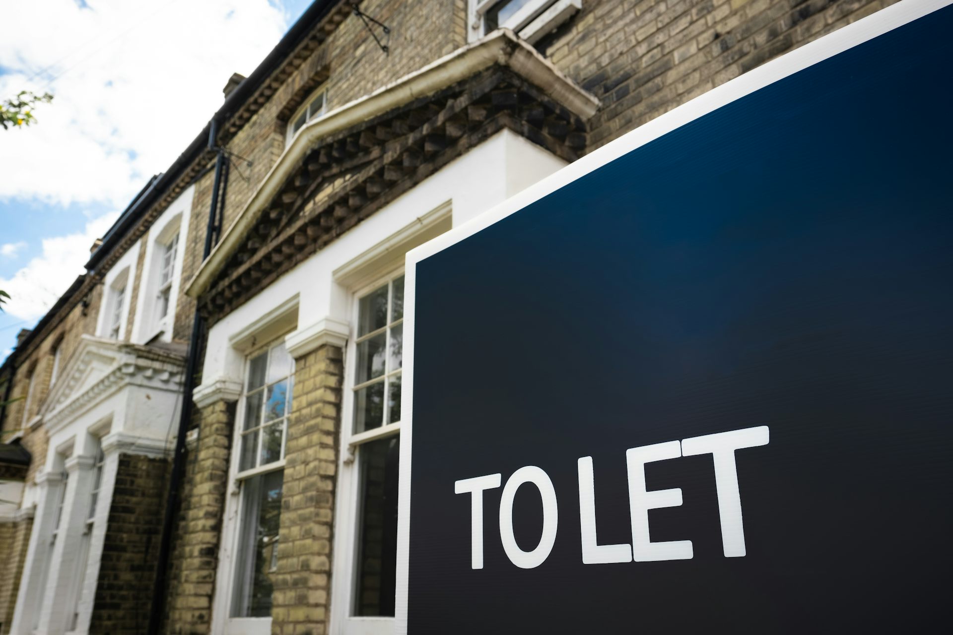 A blue To Let sign outside of a terraced house