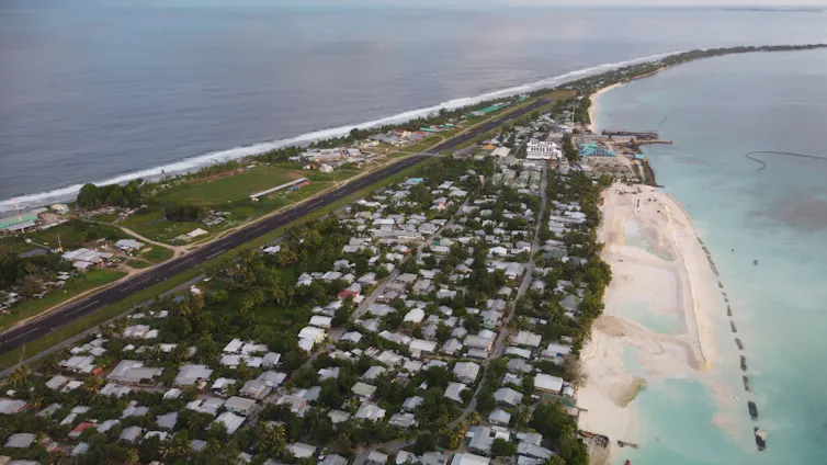 An aerial image of the airstrip alongside homes in the small, narrow country of Tuvalu.