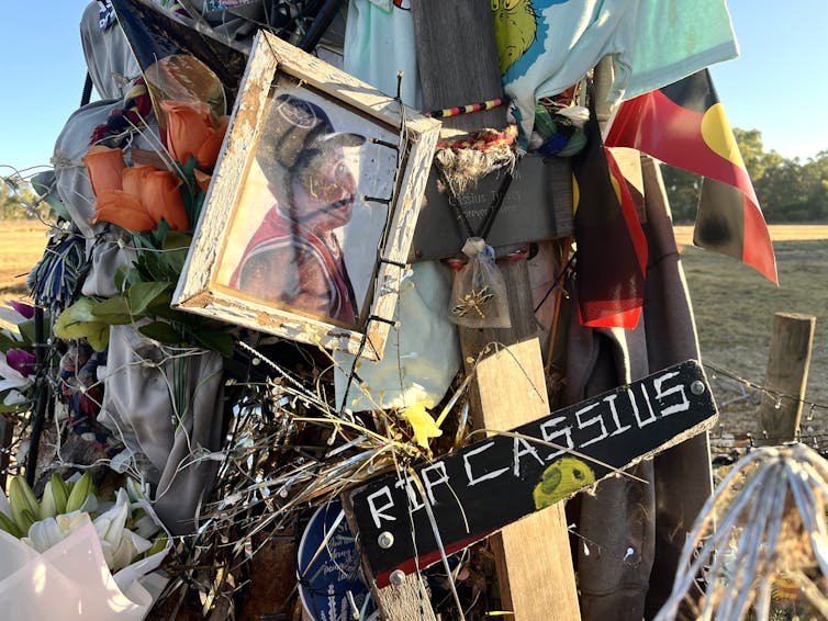 A pole covered in photos, Aboriginal flags and wood that says RIP Cassius
