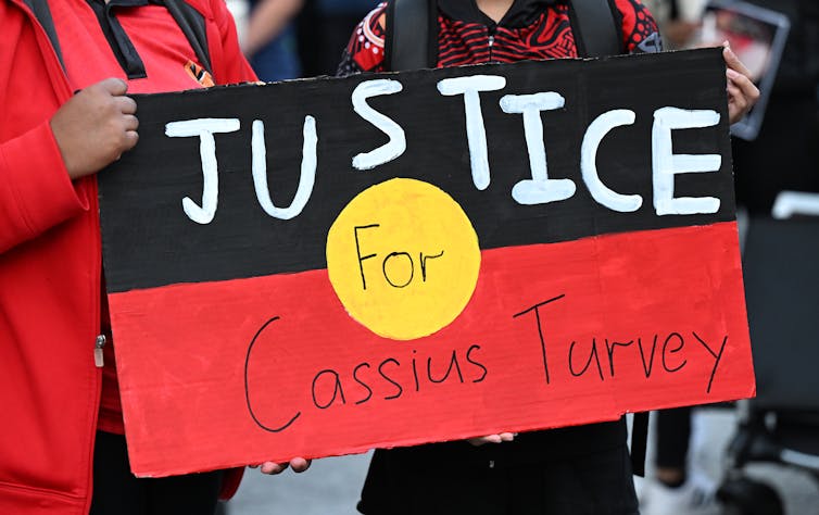 An Aboriginal flag sign reading justice for Cassius Turvey