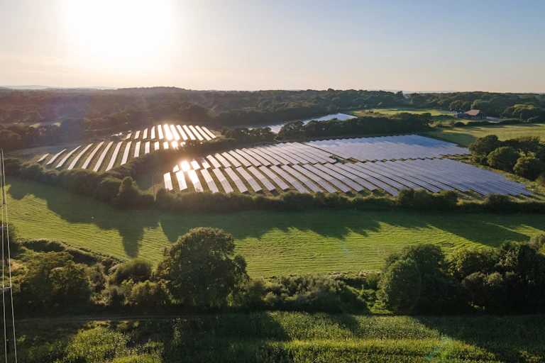 aerial shot of a solar farm in england against a setting sun