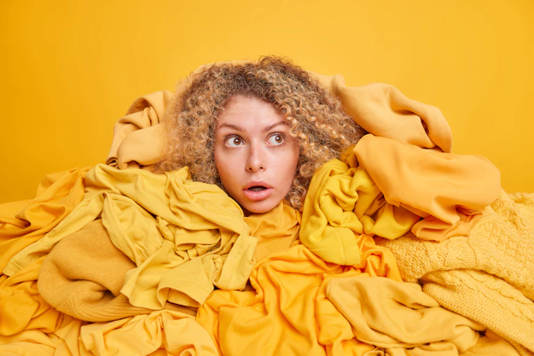 Woman's head peers out from pile of yellow clothes.