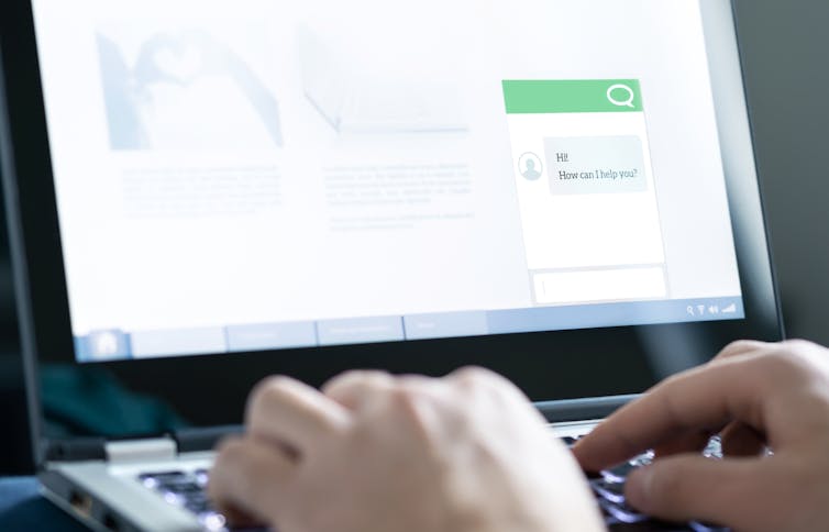 A pair of hands typing on a laptop, which displays a chat box on a website with a message that says 'Hi! How can I help you?'