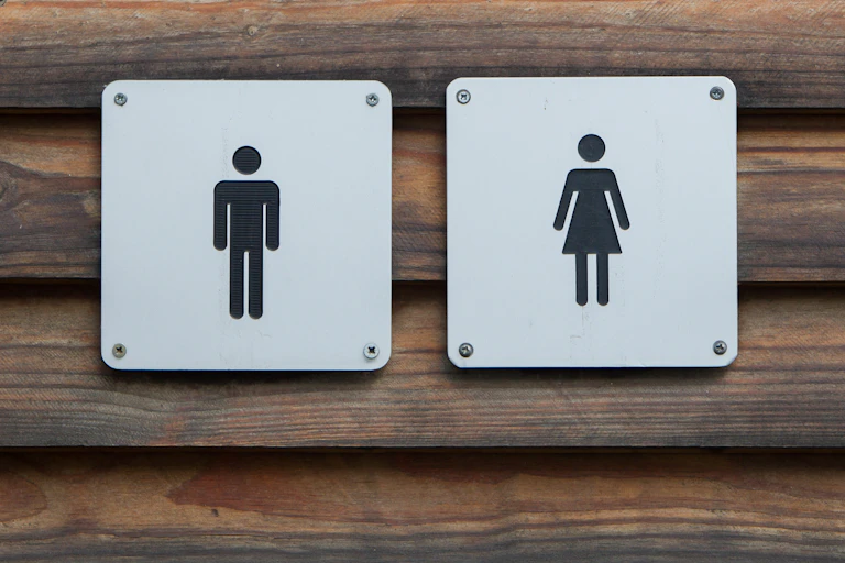 Male and female toilet signs on a log wall.