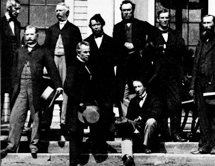 La foto en blanco y negro muestra a los hombres frente al edificio.