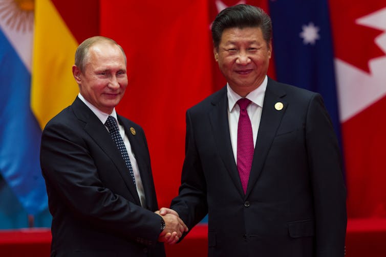 Vladimir Putin and Xi Jinping shaking hands.