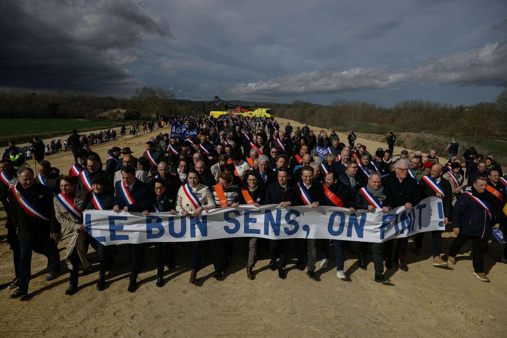 On voit une foule en marche avec des élus et une banderole «le bon sens, on finit»
