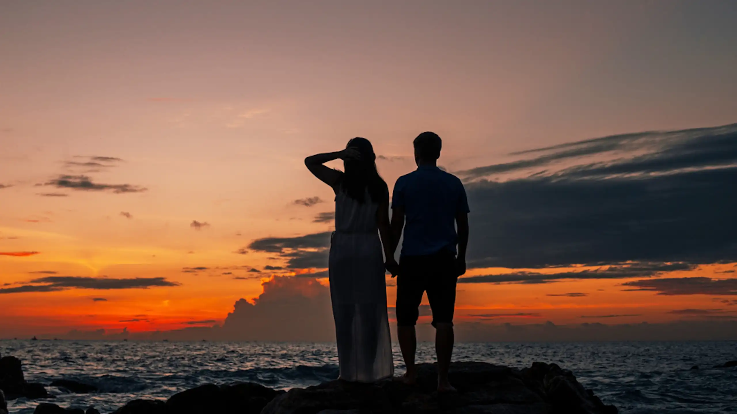 Silhouette de couple adolescent sur une plage au coucher de soleil
